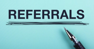 The word "referrals" printed in capital letters and underlined with a pen that lays on the paper.