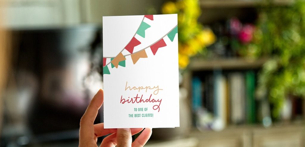 A hand holds a card that says "Happy birthday to one of the best clients"