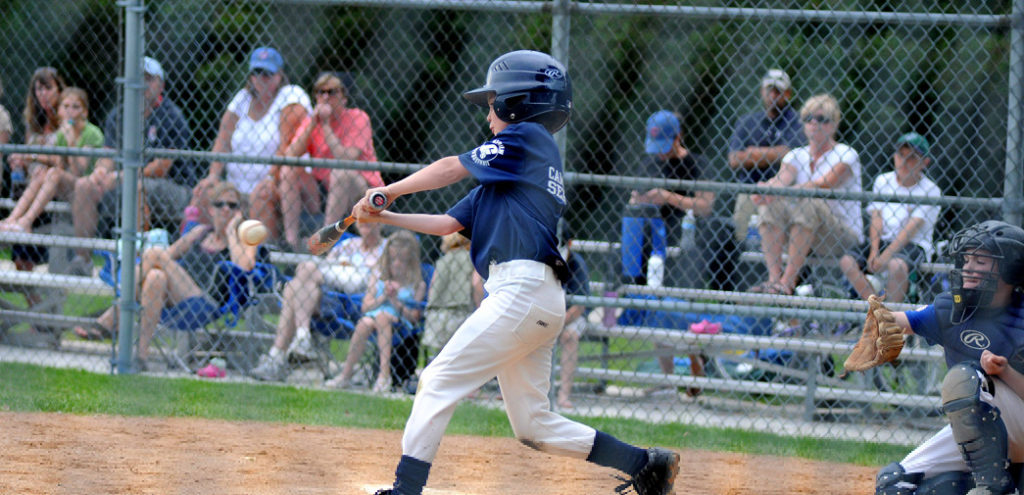 A child at a little league baseball game hits a ball