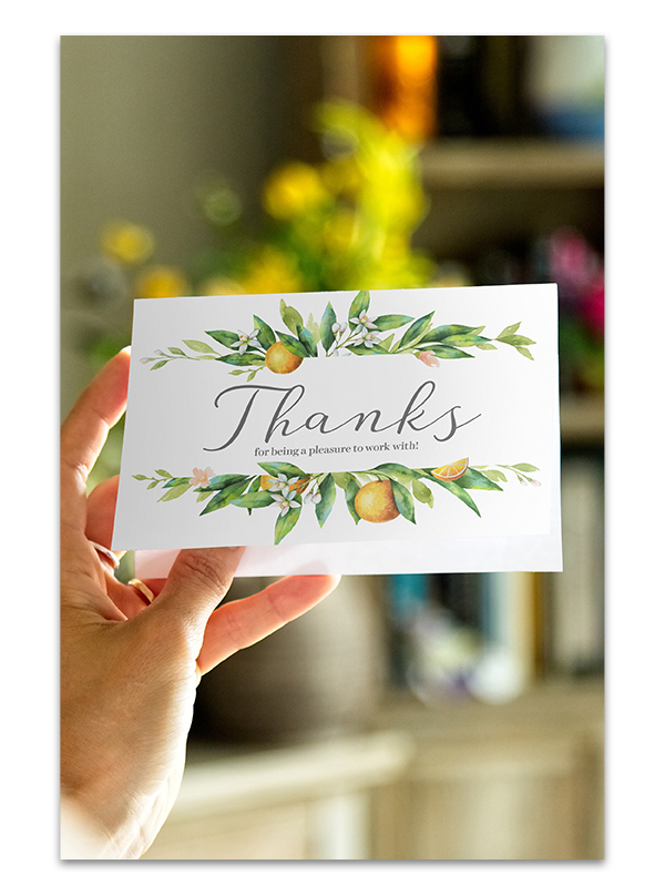A hand holds up a white greeting card with the word "Thanks" printed on the front
