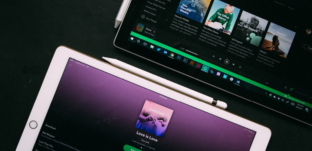 A pair of iPads featuring the Spotify app