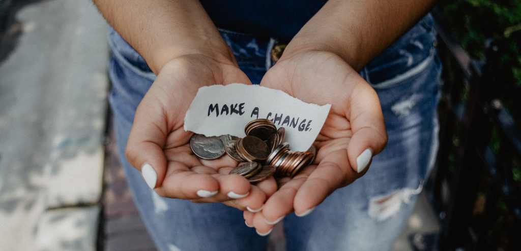 A professional collects money for a charitable cause; A handful of change along with a scrap of paper that says "Make a Change"