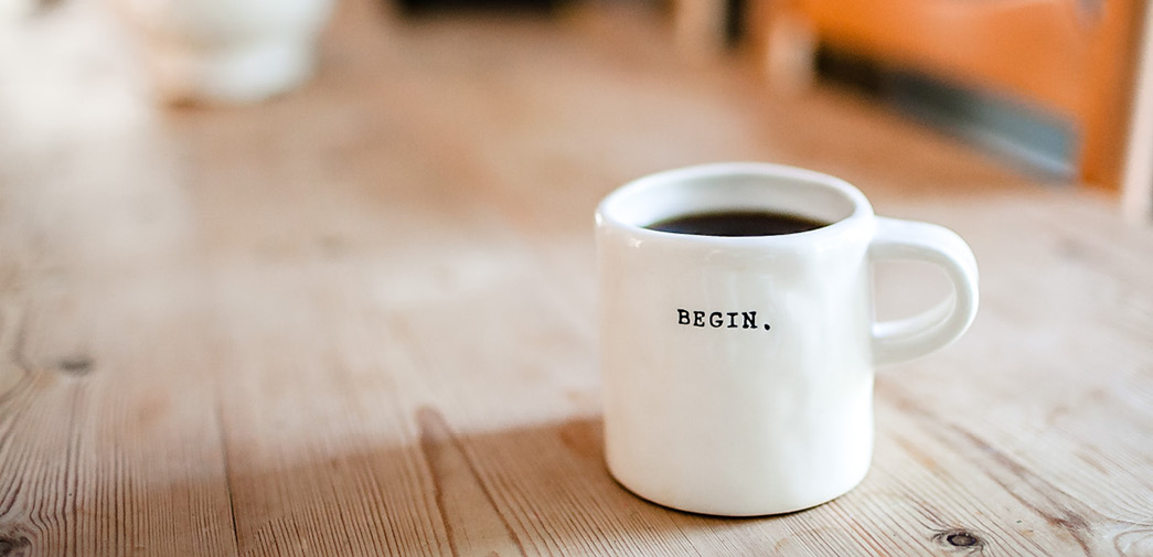 A cup of coffee with the word "Begin" written on it