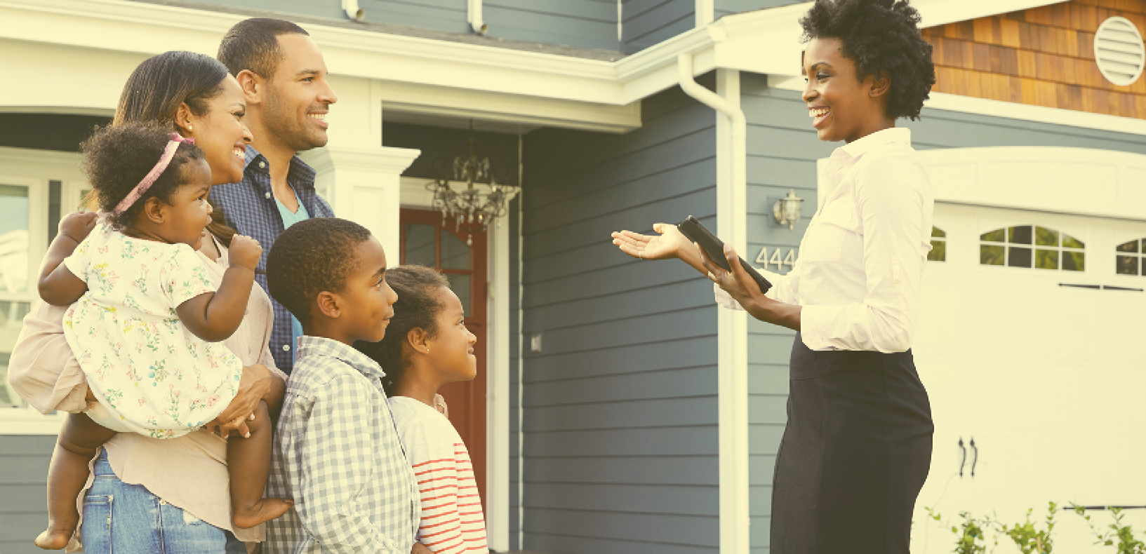 Real estate agent in front of home speaking to a family of mom, dad, young boy, and young girl