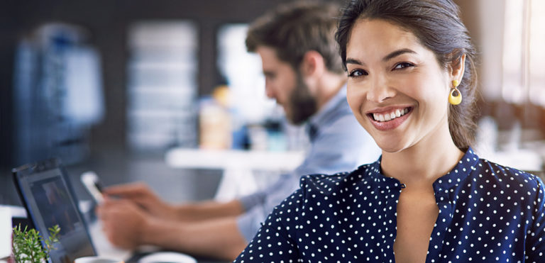 woman in blue shirt looking at camera with man behind her