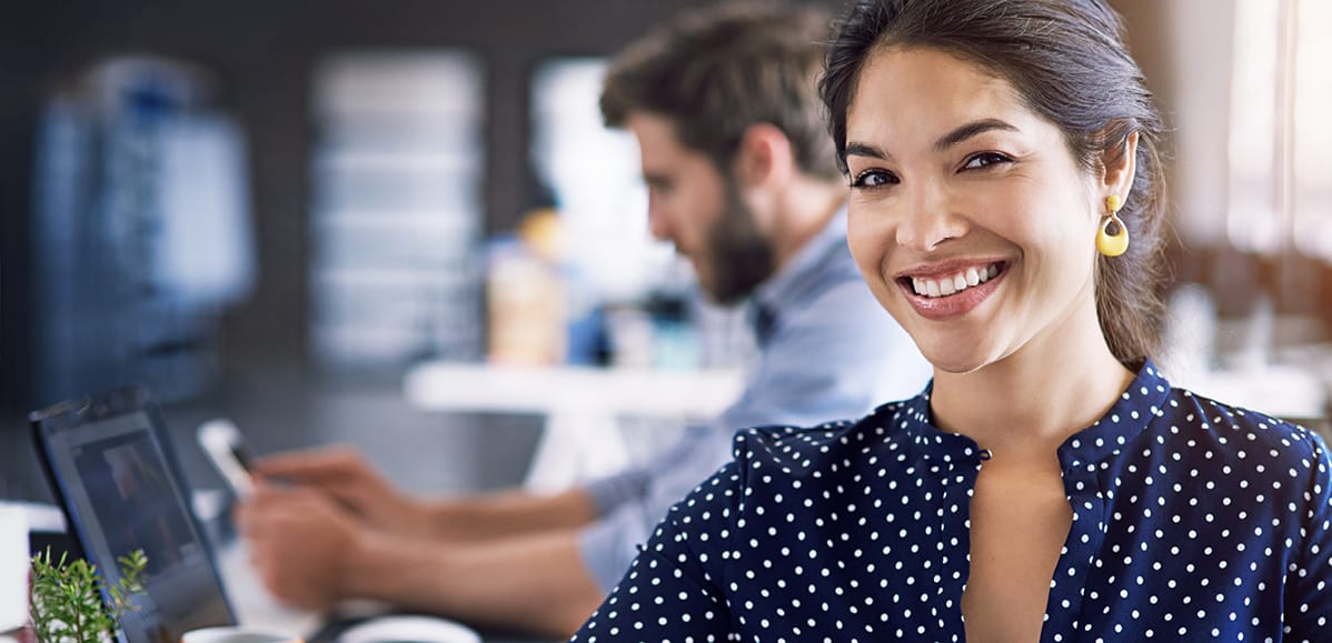 woman in blue shirt looking at camera with man behind her